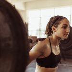 Healthy woman at gym exercising with barbell